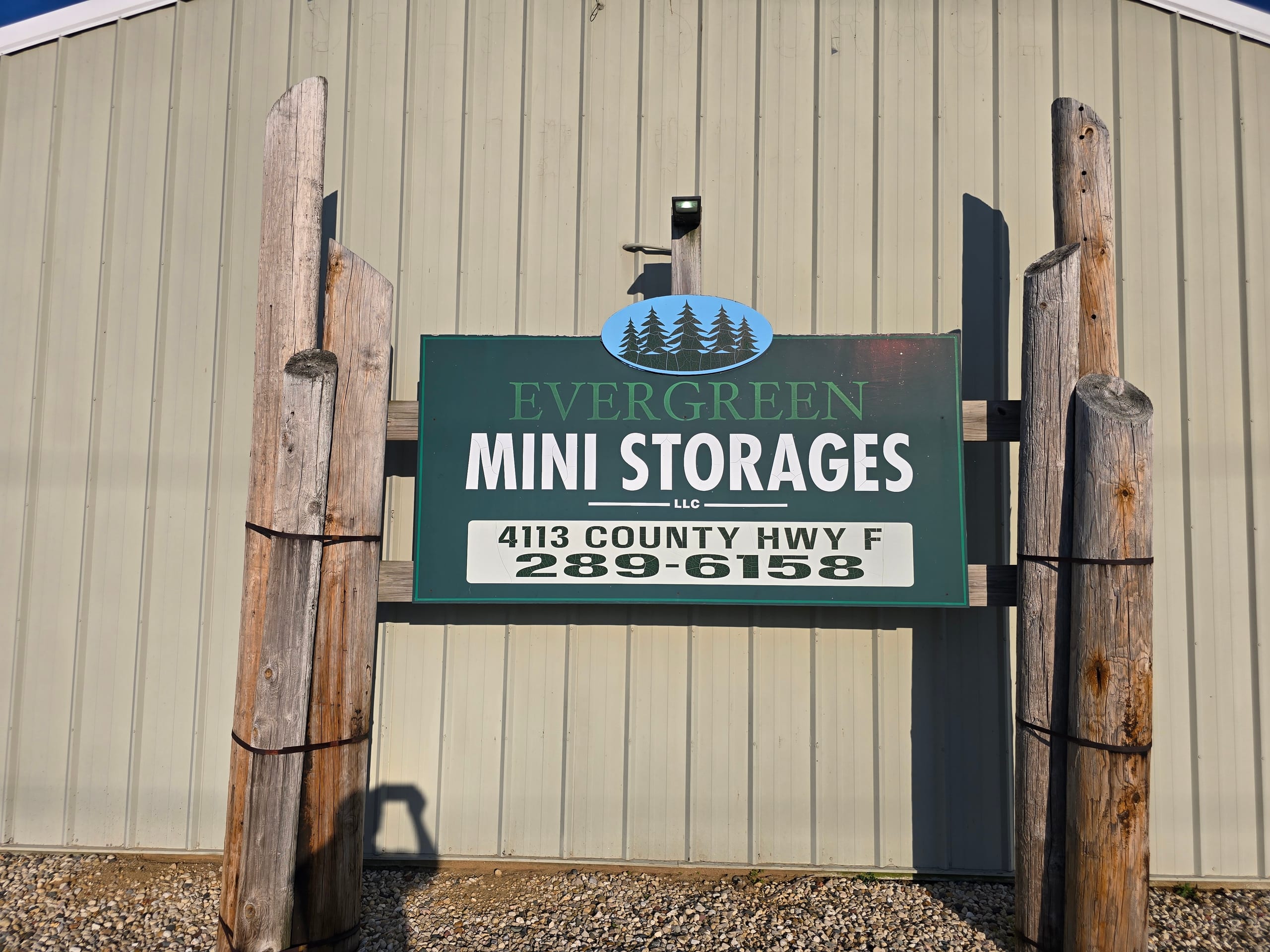 Evergreen Mini Storages LLC sign mounted on the facility building with the address and phone number